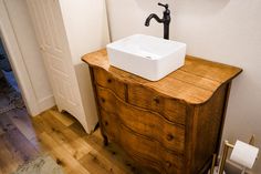 a bathroom sink sitting on top of a wooden dresser