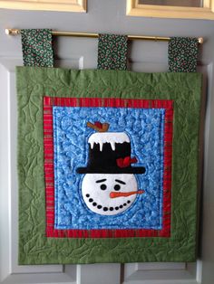 a quilted snowman hanging on the wall