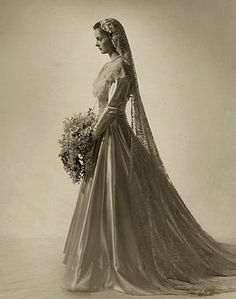 a black and white photo of a woman in a wedding dress holding a flower bouquet