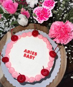 a cake with the words aris baby on it surrounded by pink carnations