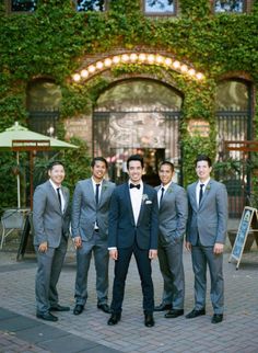 a group of men standing next to each other in front of a building with ivy growing on it