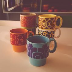 four coffee cups sitting on top of a table next to each other in front of a window