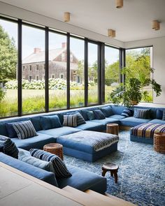 a living room filled with lots of blue couches next to large windows on the wall