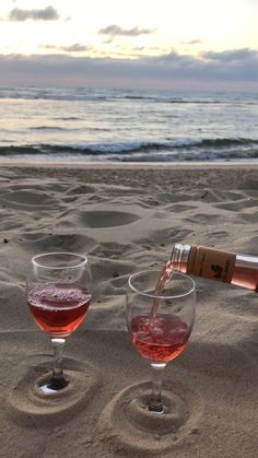 wine being poured into two glasses on the beach