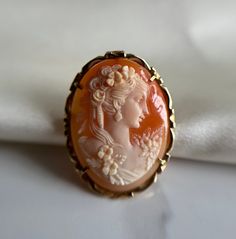 Incredible hand carved oval shell cameo, vibrant orange colour with white figure of a lady holding a rose.  Pre-loved item, some scratches on the back of the shell Size (approx.): 3.5cm tall, 2.5cm wide Stamped 585 14KT Gold Weight: 4.780g **FREE shipping within Canada and USA** If you have any questions or concerns, please do not hesitate to contact us. We will be more than happy to help you and answer any inquiries.  We invite you to check out our shop for more fabulous items! White Oval Cameo Brooches, Collectible Oval Cameo Brooch, Collectible Oval Cameo Brooches, Oval Cameo Brooches As Gift, Carved Oval Brooch As Gift, Carved Oval Brooch For Gift, Carved Oval Brooches As Gift, Oval Cameo Brooch For Anniversary, Vintage Orange Brooches For Wedding