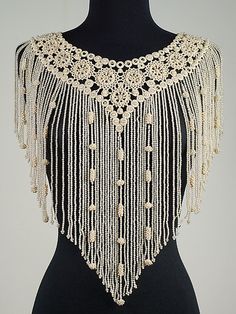 a black mannequin with white beads on it's neck and fringes