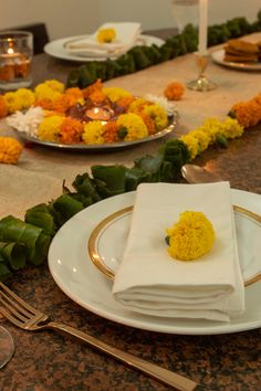 the table is set with plates, silverware and yellow flowers on each placemat