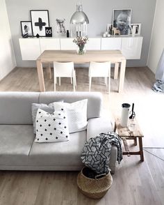 a living room filled with white furniture and pictures on the wall above it's coffee table