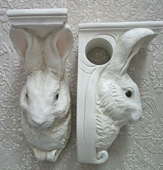 two white ceramic rabbits are on the wall