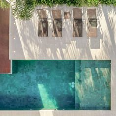 an overhead view of a swimming pool with green plants growing on the wall above it