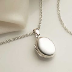 "Our beautiful Sterling Silver Oval Locket has a wonderfully classic design making it a timeless piece which will be loved and treasured for years to come. The front and back of this locket has a luxurious plain polished surface, perfect for engraving a message on. This locket comes complete with a sterling silver chain available in five different lengths So why not make this a truly personal gift by having your own special message engraved, by us, on this eye catching locket. To order this locket simply select the chain length and the font you would like us to use from the drop down menus, you can select \"no engraving\" if you would like us to leave it blank. Then at the checkout enter where you would like us to engrave, front with hinge on left or back with hinge on the right and the me Elegant Oval Link Locket Necklace, Elegant Oval Locket Necklace As A Gift, Elegant Oval Locket Necklace For Gift, Timeless Oval Locket Necklace For Gift, Timeless Oval Locket Necklace, Elegant Oval Pendant Locket Necklace For Keepsake, Classic Oval Link Locket Jewelry, Timeless Oval Engraved Locket Necklace, Classic Locket Necklace With Polished Finish For Formal Occasions