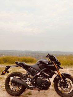 a black motorcycle parked on top of a dirt field