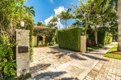 the driveway is lined with trees and bushes, along with a brick walkway that leads to an entrance