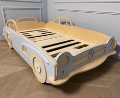 a child's bed made out of wood with wheels on the bottom and sides