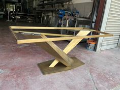 a table that has been made out of wood and is sitting on the ground in front of a garage