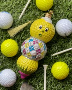 several golf balls and tees on the ground with faces painted on them, including one yellow