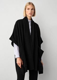 One of the most versatile pieces of the season, this poncho feels like a blanket, but with the fit of an oversized cardigan. The sleeves are loose and fall just over each shoulder, and the style features generous patch pockets that make for the perfect place to warm those fingers on colder days of the year. Throw on over a dress or layer on top a long-sleeve shirt or sweater. This poncho has been designed to fit to a wide range of body types, and is offered in a single size to flatter all. Detai Open Poncho Outfit, Chic Oversized Cashmere Cape, Oversized Cashmere Wraps For Winter, Black Shawl For Fall, Chic Oversized Cape With Batwing Sleeve, Black Shawl Wrap For Fall, Chic Oversized Outerwear With Batwing Sleeve, Oversized Cashmere Cape With Long Sleeves, Oversized Cape Cardigan For Fall