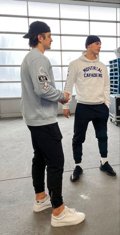 two young men standing next to each other in front of a garage door holding hands