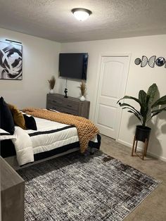 a bed room with a neatly made bed and a flat screen tv