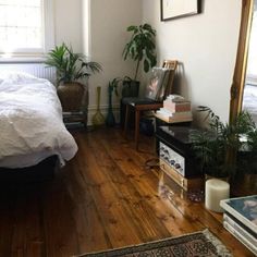 a bed room with a neatly made bed next to a mirror and some potted plants