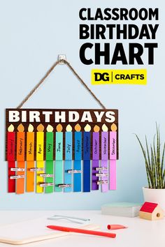 a classroom birthday chart hanging on a wall next to a potted plant and pencils