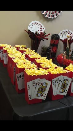 a table topped with red bags filled with popcorn and cards next to vases full of candy