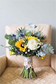 a bouquet of flowers sitting on top of a couch next to a chair with a pillow