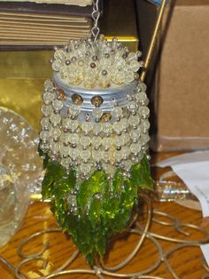 a glass vase with beads and leaves on a table next to a candle holder that is hanging from a chain