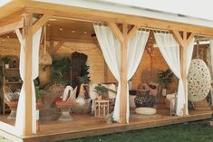 a porch covered in white curtains and furniture