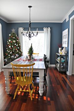 a dining room table with yellow chairs and a christmas tree