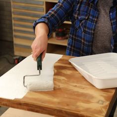 a person using a paint roller on a piece of wood