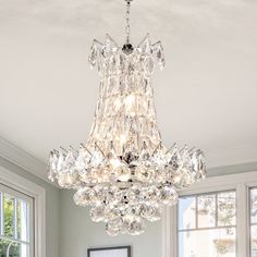 a chandelier hanging from the ceiling in a living room with white walls and windows