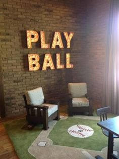 the play ball room is decorated with neon letters and baseball themed chairs, along with a green area rug