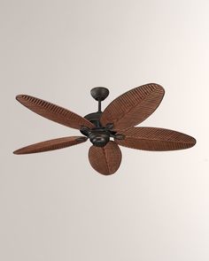 a ceiling fan that is brown and has four leaves on it, in front of a white wall