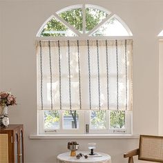 a living room with two chairs and a table in front of a large arched window