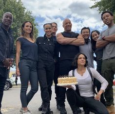 a group of people standing next to each other with a cake in front of them