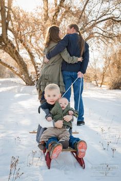 a woman and two children on a sled in the snow