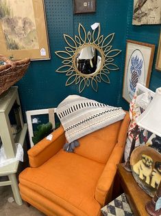 an orange chair sitting in front of a blue wall with pictures on it and a mirror