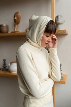 a woman in a white hoodie is looking down at her hand on her head