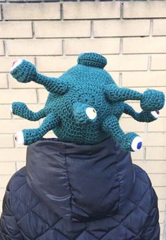 an octopus stuffed animal sitting on top of a jacket in front of a brick wall