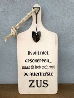 a wooden sign with the words zus on it hanging from a rope against a wall