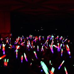 a large group of people standing in the dark with lights on their bodies and hands