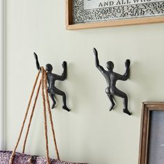 two metal figurines are hanging on the wall next to a chalkboard and rope