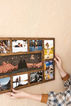 a person holding up a wooden photo collage with pictures on the wall behind them