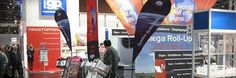 people are walking around an exhibit at a trade show with banners and advertisements on the walls