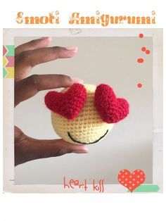 a hand holding a small crocheted toy with hearts on it's head