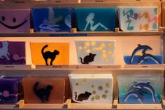 the shelves are filled with different types of handmade soaps and cat silhouettes