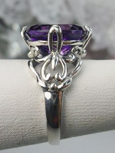 Natural Purple Amethyst RingSmall Fat Oval Design#D111 Inspired by Gothic designs, this stunning antique reproduction ring is crafted in sterling silver. This gorgeous ring is set with a flawless oval-cut natural purple amethyst. The stunning 3 carat weight gemstone is 11mm x 9mm. The band is marked 925 for sterling silver. Notice the beautiful silver filigree swirl setting and band. The bold style travels around the base of the gem and morphs into a solid band. The stunning gem rises above the Purple Amethyst Ring With Intricate Design, Elegant Oval Amethyst Promise Ring, Purple Amethyst Ring With Intricate Design For Promise, Purple Amethyst Promise Ring With Intricate Design, Elegant Purple Amethyst Ring With Intricate Design, Purple Promise Ring With Intricate Design, Purple Intricate Design Promise Ring, Oval Amethyst Sterling Silver Ring For Formal Occasions, Sterling Silver Amethyst Promise Ring With Intricate Design