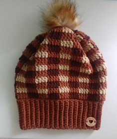 a brown and white knitted hat with a pom - pom on top