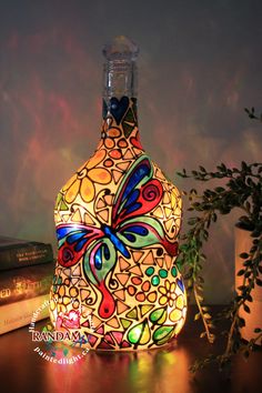 a colorful glass bottle sitting on top of a table next to a plant and books